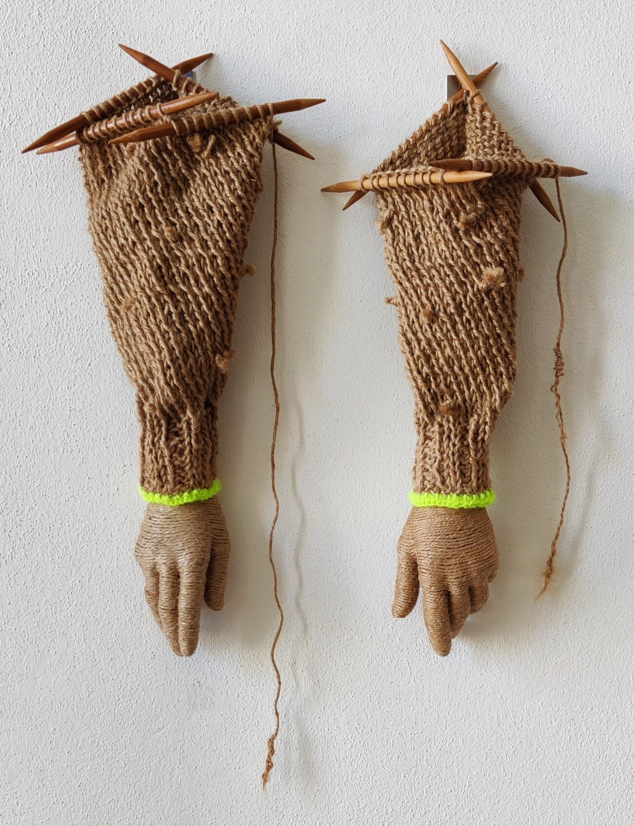 Sculptural set of two artificial arms made of rope, wool, hands, and wooden knitting needles. Artwork by contemporary artist Nanon Morsink.