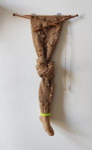 Sculptural work titled Artificial leg by contemporary artist Nanon Morsink, made from rope, wool, a foot, and wooden knitting needles.