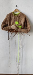 Sculptural work titled Under construction by contemporary artist Nanon Morsink, made from rope, wool, wooden knitting needles, and hands.