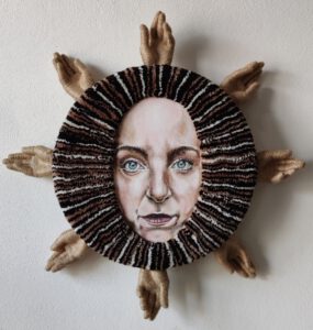 Fiber art sculpture titled “I Am the Sun” by Nanon Morsink, from the Soft Series. Contemporary textile wall piece made with tufted wool, acrylic paint, rope, and sculpted hands on board. 70 cm diameter, 2025. Bold and tactile mixed media art.